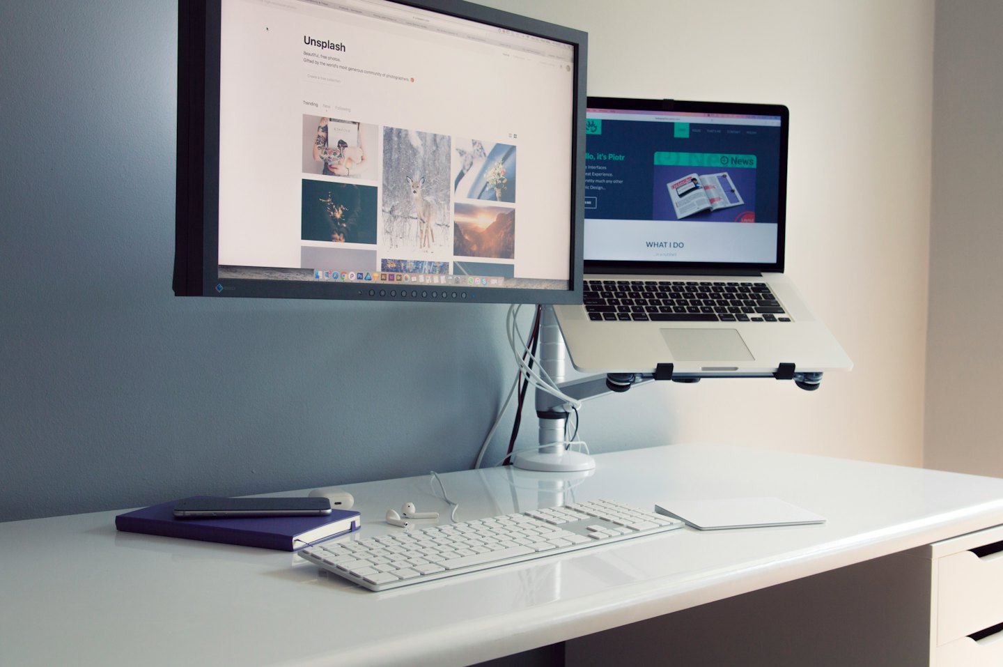 Ein aufgeräumter Schreibtisch mit zwei Monitoren und einem Laptopständer.